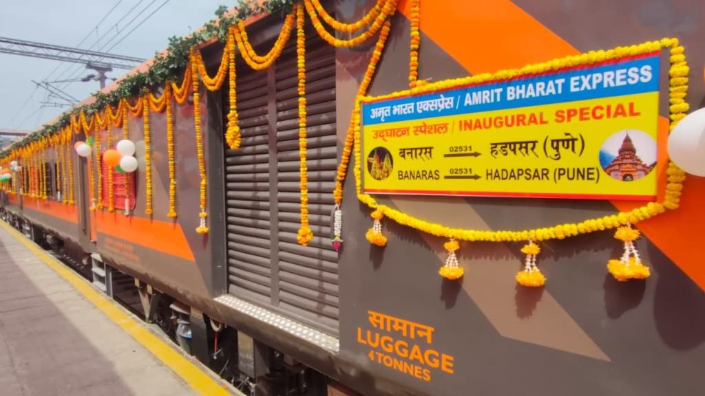 Side view of the luggage van and passenger coach of the Banaras-Hadapsar (Pune) Amrit Bharat Express Inaugural Special, displaying the yellow and orange destination board with regional landmarks.