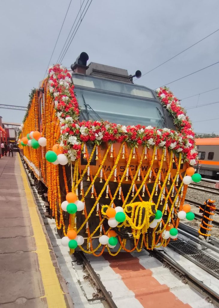 Front view of the WAP-5 locomotive of the Banaras-Hadapsar Amrit Bharat Express decorated with orange marigolds and tricolor balloons for its inaugural run in April 2026.