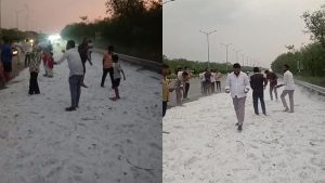 A group of people standing and walking on a thick layer of white hail covering the Hyderabad Outer Ring Road (ORR), making the highway look like a snow-covered landscape during a severe summer hailstorm.
