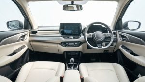 An expansive, wide-angle photograph capturing the entire modern dashboard and premium beige and dark grey interior cabin of the 4th-Gen Maruti Suzuki Dzire, highlighting its unbranded central touchscreen and multi-function steering wheel.