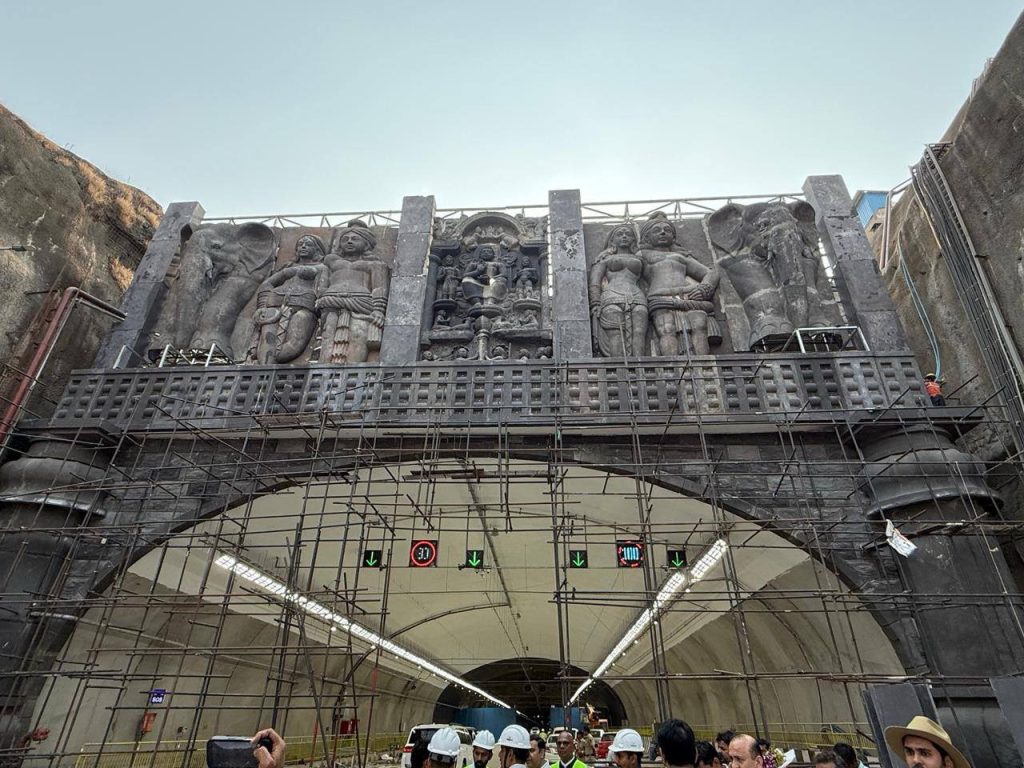 A detailed view of the ornamental stone carvings above the tunnel entrance, featuring traditional Indian motifs, elephants, and figures inspired by the Karla Caves and Maratha heritage.