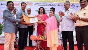 A group of officials standing on a stage, holding an official certificate and a plaque to celebrate the record-breaking construction of a high-rise residential building by the PMRDA. A large banner in the background displays the logos for the Asia Book of Records and the India Book of Records.