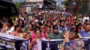 A large crowd of local residents and women marching in the streets, holding black banners and protesting the tragic assault and murder of the four-year-old girl in Pune's Bhor tehsil.