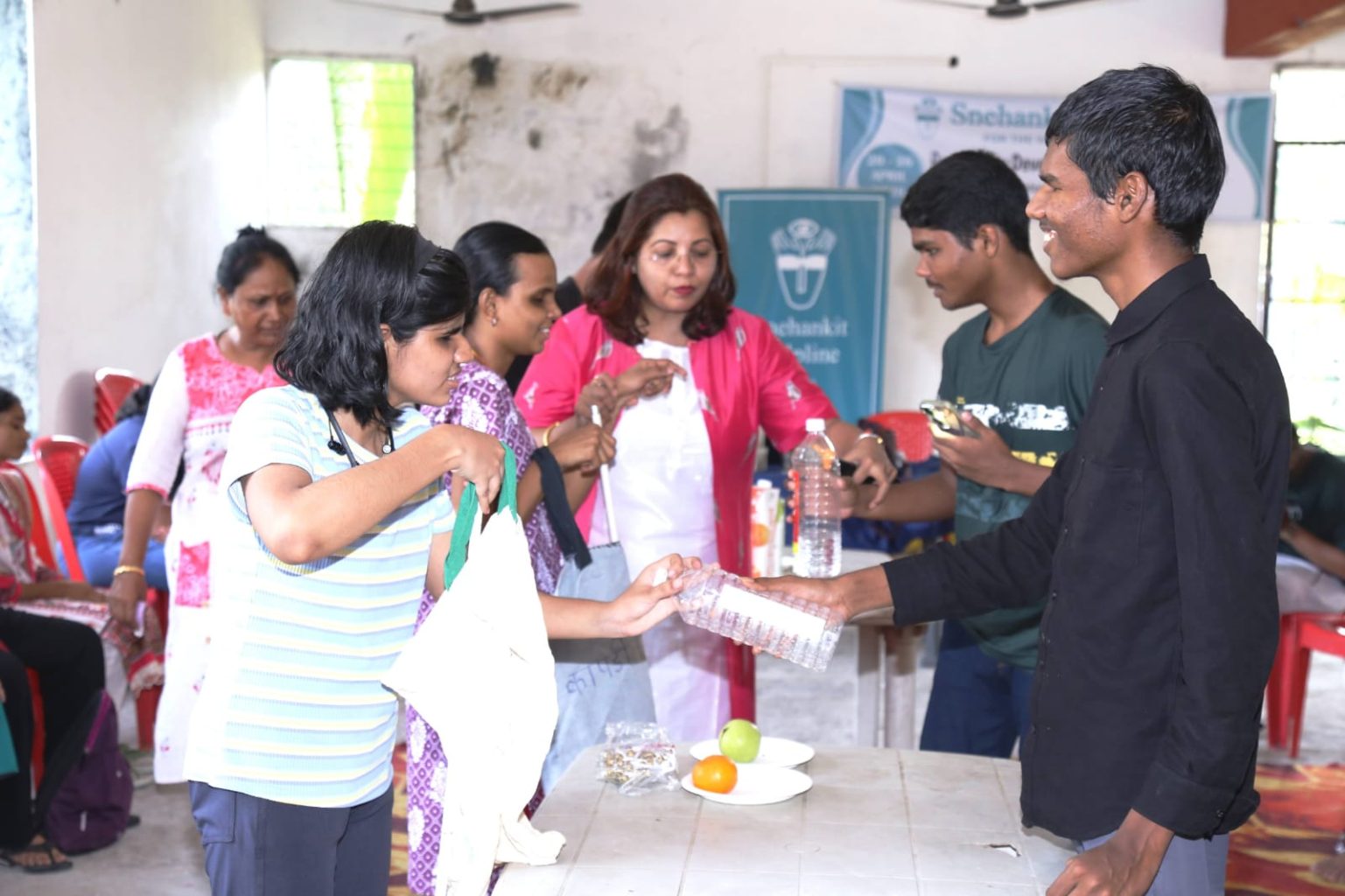 Visually impaired students participate in a tactile environmental awareness activity at the Sparsh Shakti workshop. A female student holds an eco-friendly cloth bag while a male student handles a plastic water bottle, demonstrating the "Friends vs Foes" lesson on sustainability and climate action.
