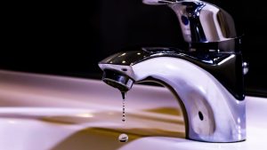 A chrome faucet with just a few drops of water dripping.