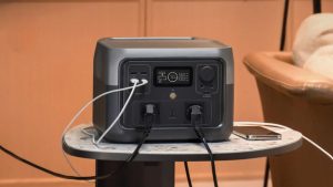 A portable power station placed on a table with multiple devices drawing power using USB and AC ports.