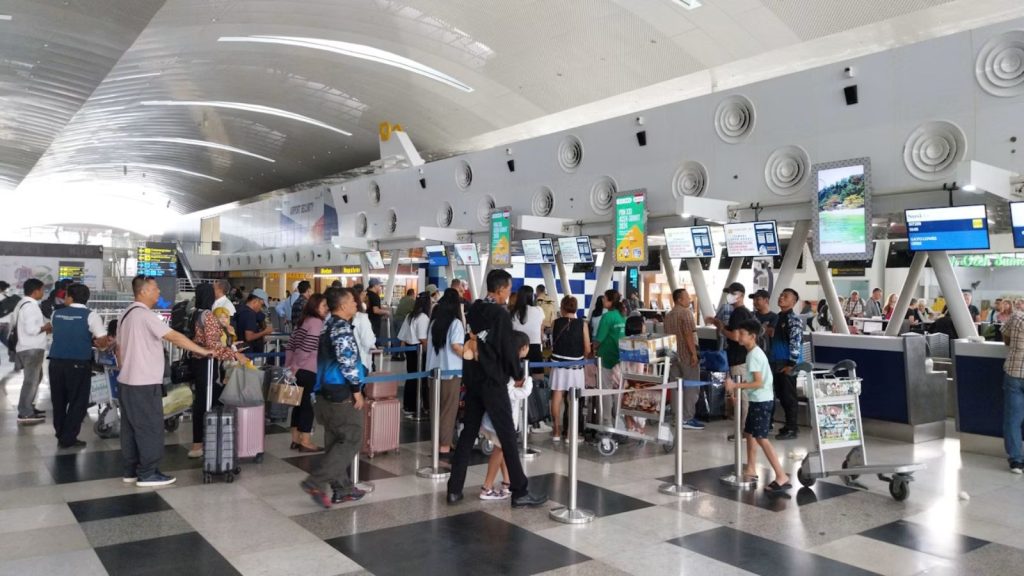 A scene at an airport showing passengers queuing up at check in counters.