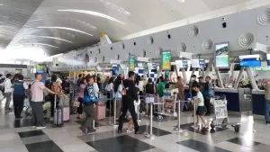 A scene at an airport showing passengers queuing up at check in counters.