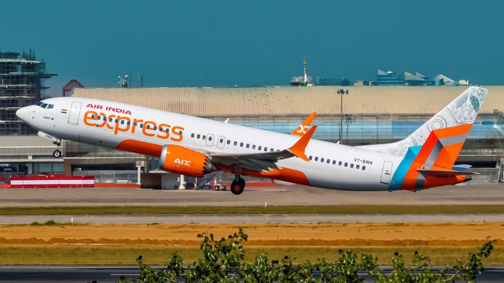An Air India Express Boeing 737 Max 8 taking off from Pune airport runway with airline's orange and white livery.