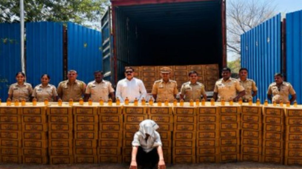 An alleged convict sits with head covered in front of many liquor boxes that were seized by Pune Excise department.