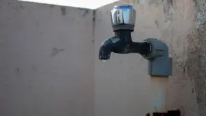 Close-up of a dry outdoor water tap with a single hanging droplet, symbolizing a water shortage or supply disruption.